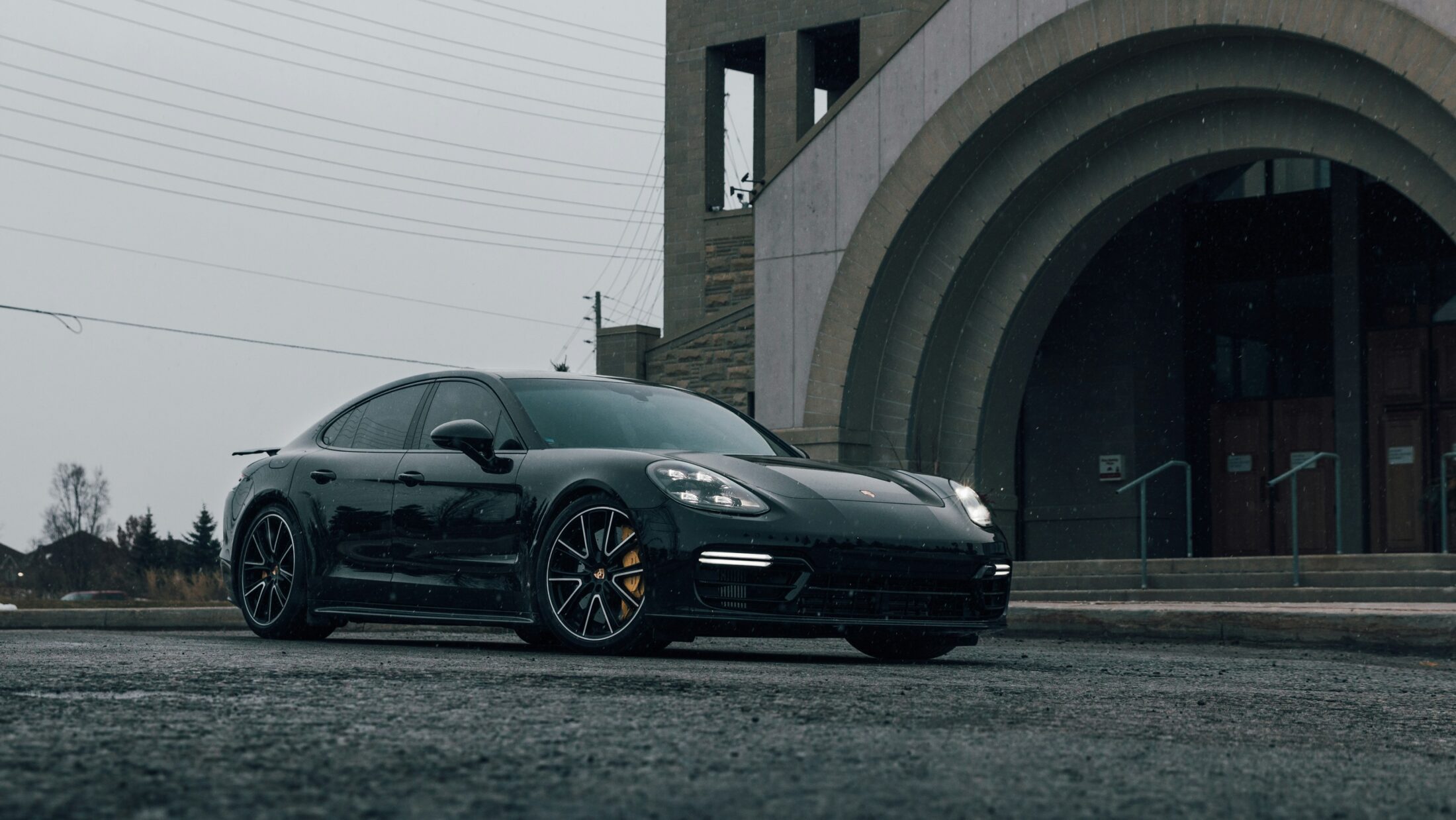 Porsche Panamera GTS noire devant une arche en pierre