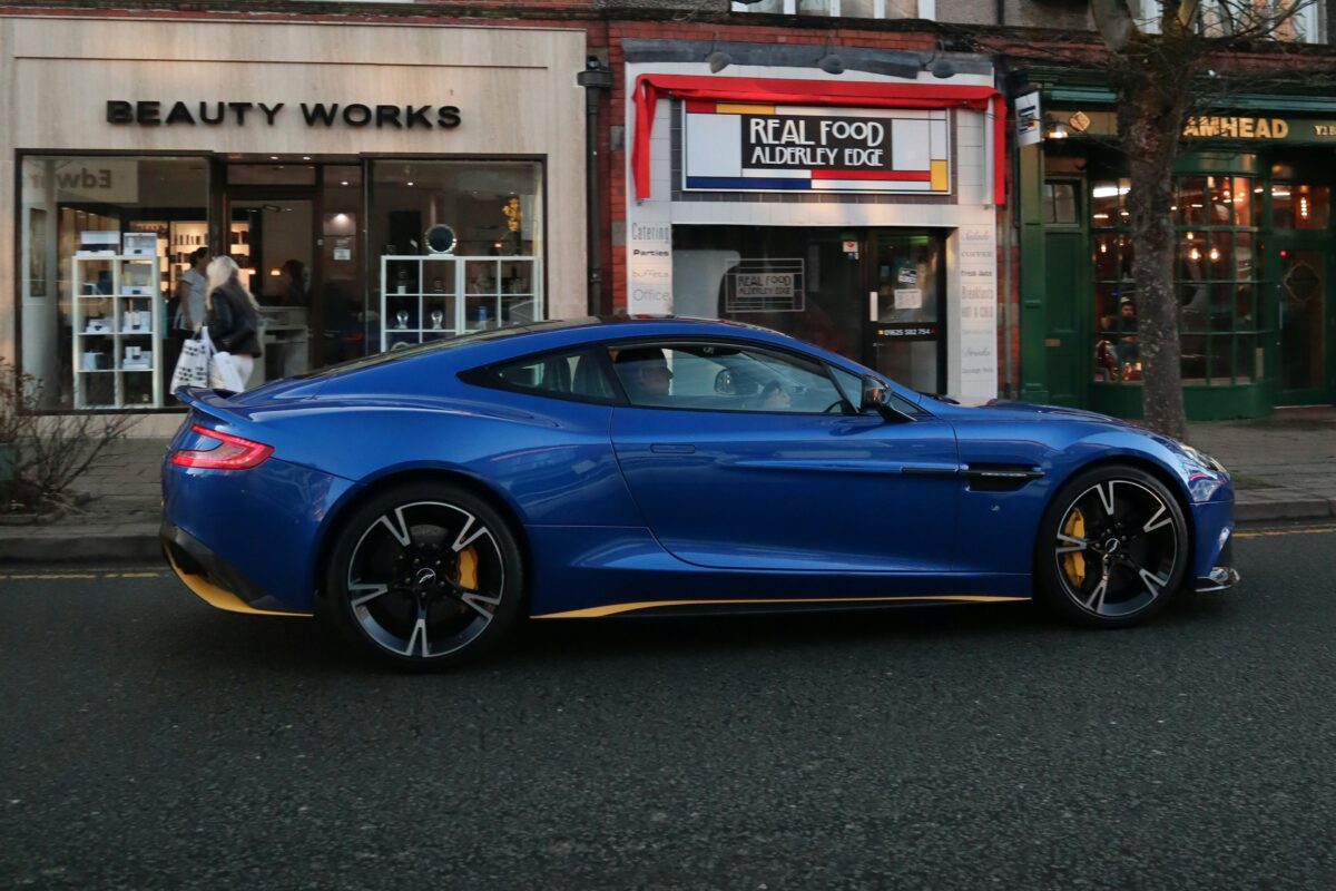 Aston Martin Vanquish S bleue dans une rue commerçante