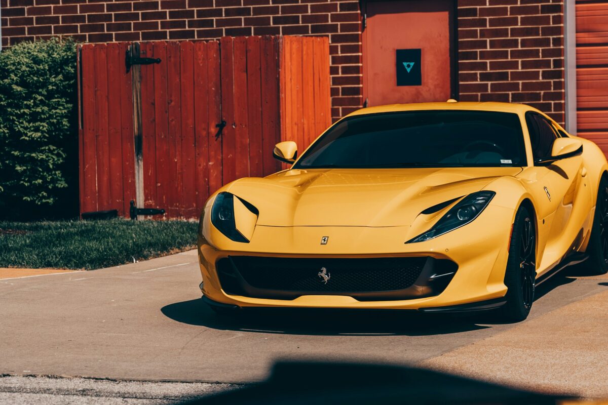 Ferrari 812 Superfast jaune devant une porte de grange rouge