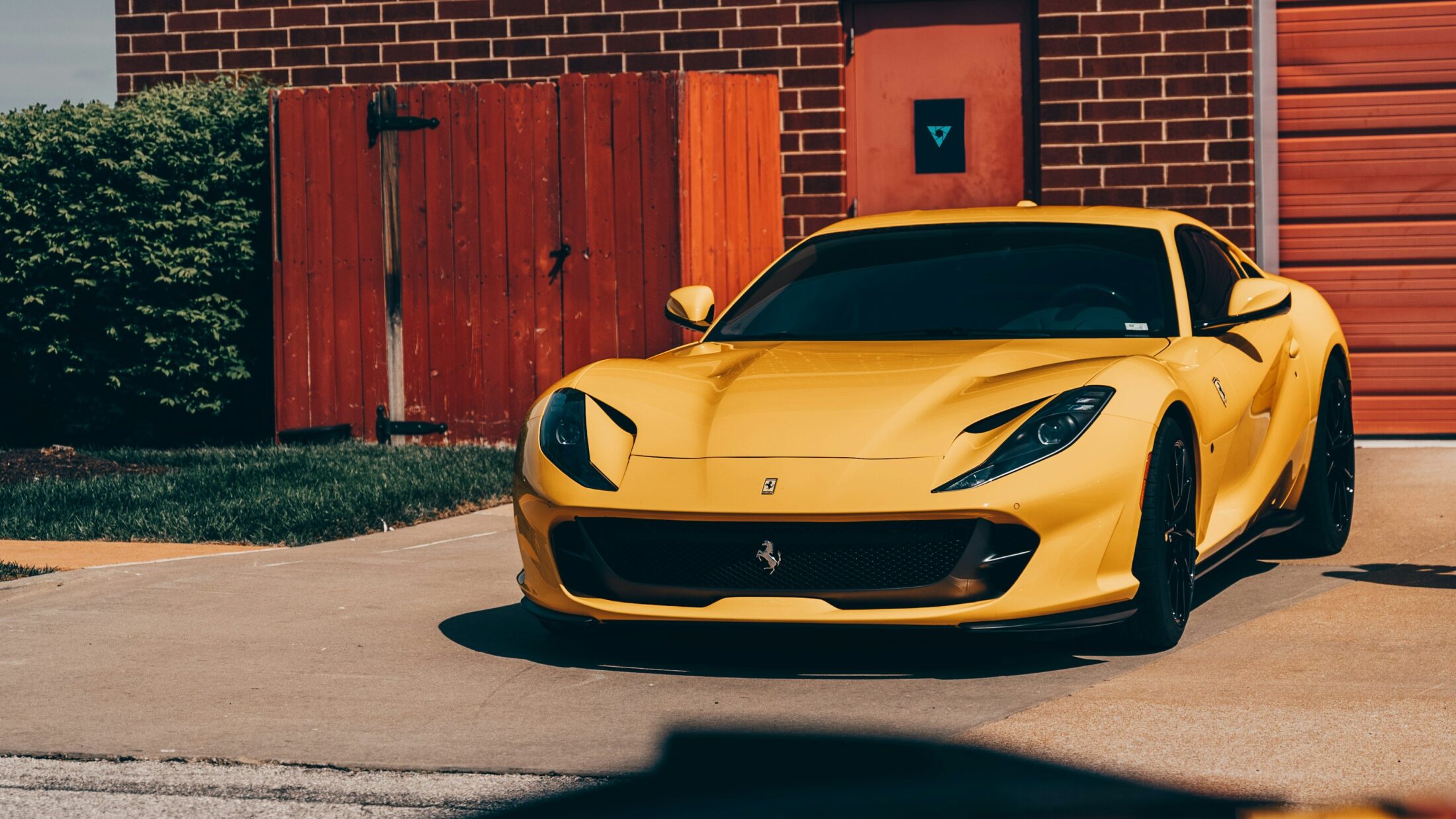 Ferrari 812 Superfast jaune devant une porte de grange rouge